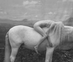 a black and white photo of a woman hugging a horse