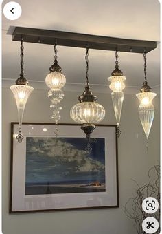 a chandelier hanging from the ceiling in a living room with pictures on it