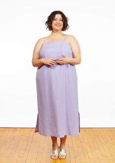 a woman in a purple dress standing on a wooden floor with her arms around her waist