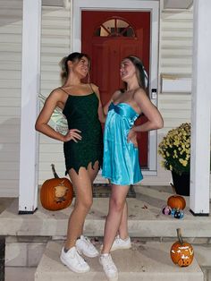 two young women standing on steps in front of a house with pumpkins behind them