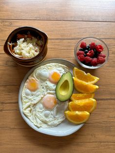 an avocado, oranges, strawberries and eggs on a plate