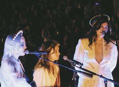 two women standing next to each other in front of microphones at a music concert