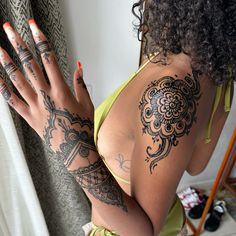 a woman with tattoos on her arm and hand is standing in front of a curtain