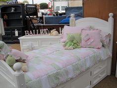 there is a white bed with pink and green bedspreads on top of it