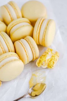 a pile of yellow and white macaroons next to a spoon