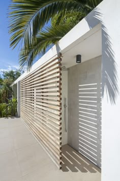 a white building with shutters on the outside and palm trees in the back ground