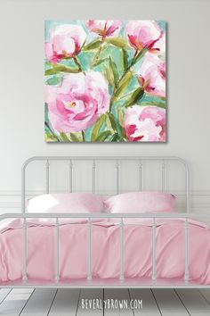 a pink bed with white sheets and pillows in front of a painting on the wall