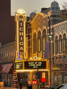 a theater marquee on the corner of a city street with cars parked in front