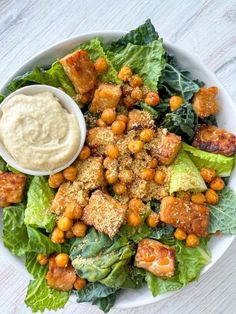 a white bowl filled with lettuce, chickpeas and some kind of sauce