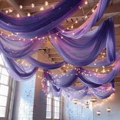 the ceiling is decorated with purple fabric and lights