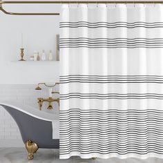 a white and black shower curtain in a bathroom next to a bathtub with a gold faucet