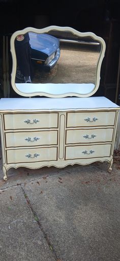 an old dresser with a mirror on it and a car parked in the garage behind it