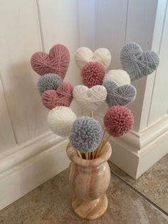 a vase filled with balls of yarn sitting on top of a floor