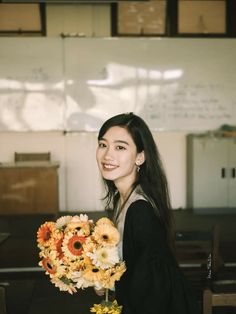 a woman holding a bouquet of flowers in front of a whiteboard