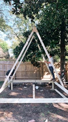 two men are building a wooden structure in the yard