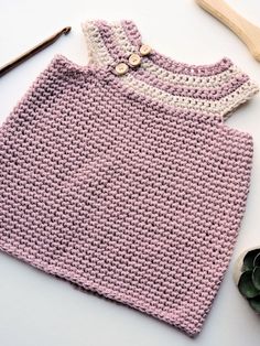 a crocheted pink sweater next to a pair of scissors