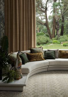 a large white couch sitting under a window next to a lush green forest filled with trees