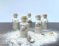 four glass bottles filled with sand and shells