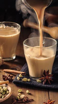 coffee being poured into two glasses with spices around them and cinnamons on the side