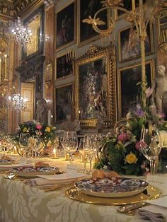 a fancy dining room set up with gold plates and place settings