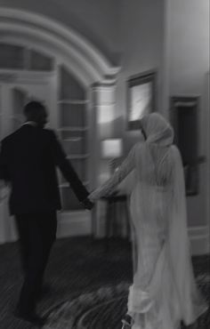 black and white photograph of a bride and groom holding hands in an elegant hotel lobby