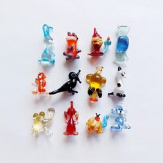 many small glass figurines are arranged on a white surface, including cats and dogs