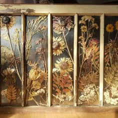 four panels with flowers painted on them in gold and silver foiled metal, set against a wooden floor