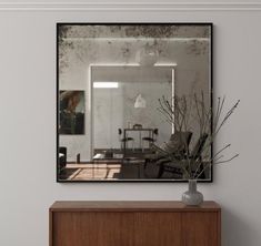 a mirror is hanging on the wall above a dresser with a vase and flowers in it