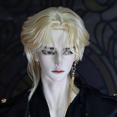 a male doll with blonde hair and black shirt, wearing gold chains on it's neck