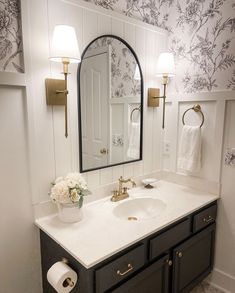 the bathroom is decorated in black and white with gold accents on the mirror above the sink