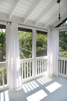 the sun is shining through the sheer curtains on this porch