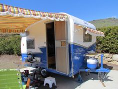 a blue and white trailer parked next to a green chair