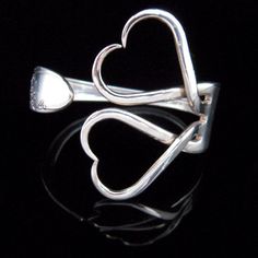 a silver ring with two hearts on it's sides and a spoon in the middle