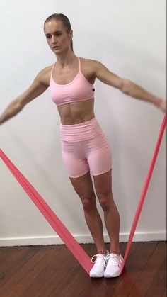 a woman in pink shirt and shorts standing on a pair of red tape with her arms stretched out