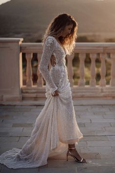 a woman in a white dress is standing on a balcony with her back to the camera