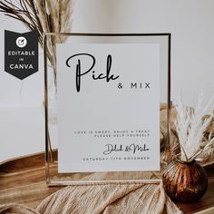 a sign sitting on top of a wooden table next to a vase filled with dry grass