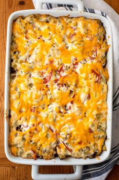 a casserole dish with cheese and other toppings in it on a wooden table