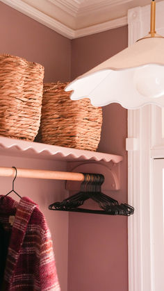 some baskets are hanging on a shelf in a room with pink walls and white trim