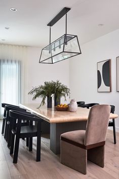 a dining room table with chairs and a plant in the center on top of it