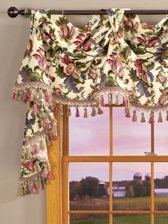 a window with curtains and tassels hanging from it's sides, in front of a sunset view