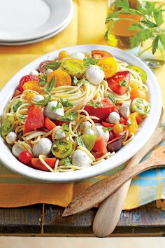 a white bowl filled with pasta and veggies on top of a wooden cutting board