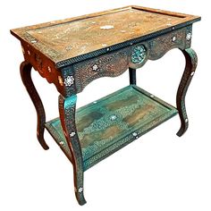 an ornate wooden table with two drawers on one side and a shelf on the other