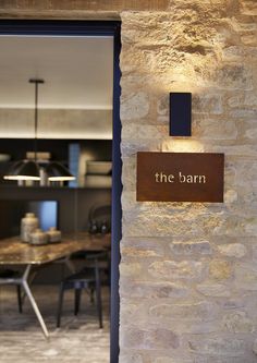 the barn sign is lit up in front of a stone wall and dining room table