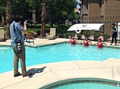 a man standing in front of a swimming pool with red life vests around him