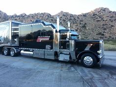 a large semi truck parked in front of a mountain