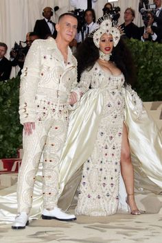 the couple is dressed up in white outfits and posing for pictures on the red carpet