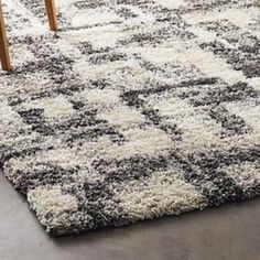 an area rug with grey and white designs on the floor in front of a wooden table