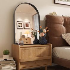 a mirror sitting on top of a wooden dresser next to a brown bed in a bedroom