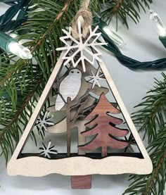 a christmas ornament hanging from a tree with snowflakes and birds on it