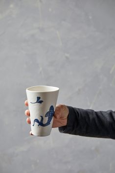 a person holding a coffee cup in their left hand with a blue design on it